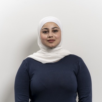 Porträt von Reham Al Khatib aus DIE ZAHNARZTPRAXIS Stralsund, im dunkelblauen Oberteil und hellem Kopftuch vor weißem Hintergrund, ausgebildete ZFA mit zusätzlichem Schwerpunkt auf Prophylaxe und professioneller Zahnreinigung