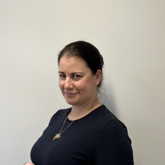 Porträt von ZFA Jenny Jager aus DIE ZAHNARZTPRAXIS Stralsund, im dunkelblauen Oberteil vor hellem Hintergrund, freundlich lächelnd und leicht seitlich zur Kamera gewandt.