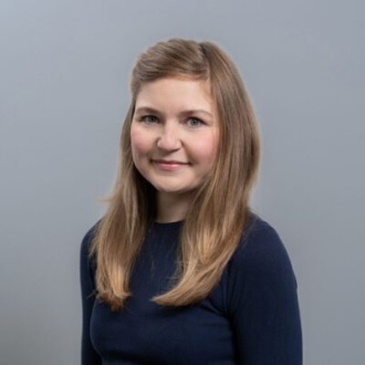 Porträt von Dr. Stefanie Motz, Inhaberin der Zahnarztpraxis DIE ZAHNARZTPRAXIS in Stralsund, freundlich lächelnd im dunkelblauen Oberteil vor neutral grauem Hintergrund, erfahrene Zahnärztin mit Schwerpunkten in Endodontie, CEREC und Implantologie.